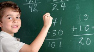 Kid doing math on chalkboard