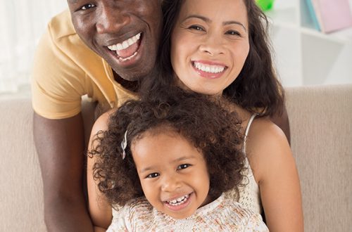 Vertical portrait of a mixed cheerful family posing at camera